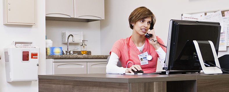 Doctor talking on telephone and using EHR app on computer