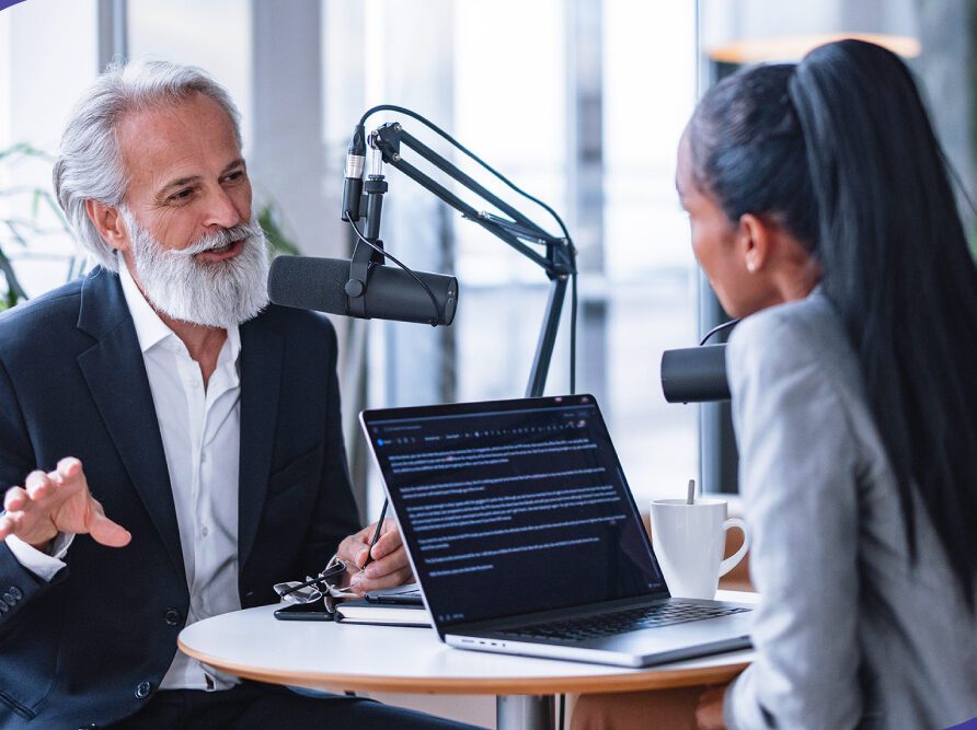 Two individuals talking with a laptop.